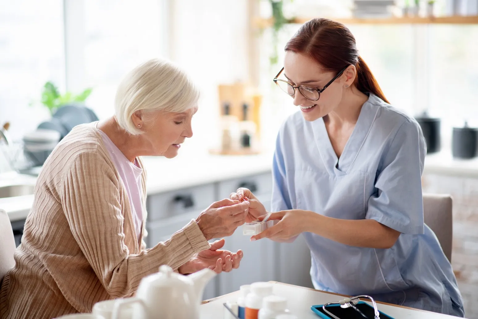 Care Professional A&S Pflegedienst - Pflegekraft mit Brille gibt älterer Dame Vitamine